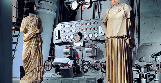 Statue di Igea ed Hestia davanti al quadro di manovra del motore diesel